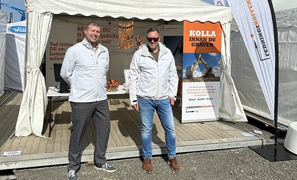 Två män står framför ett mässtält med Ledningskollenbranding